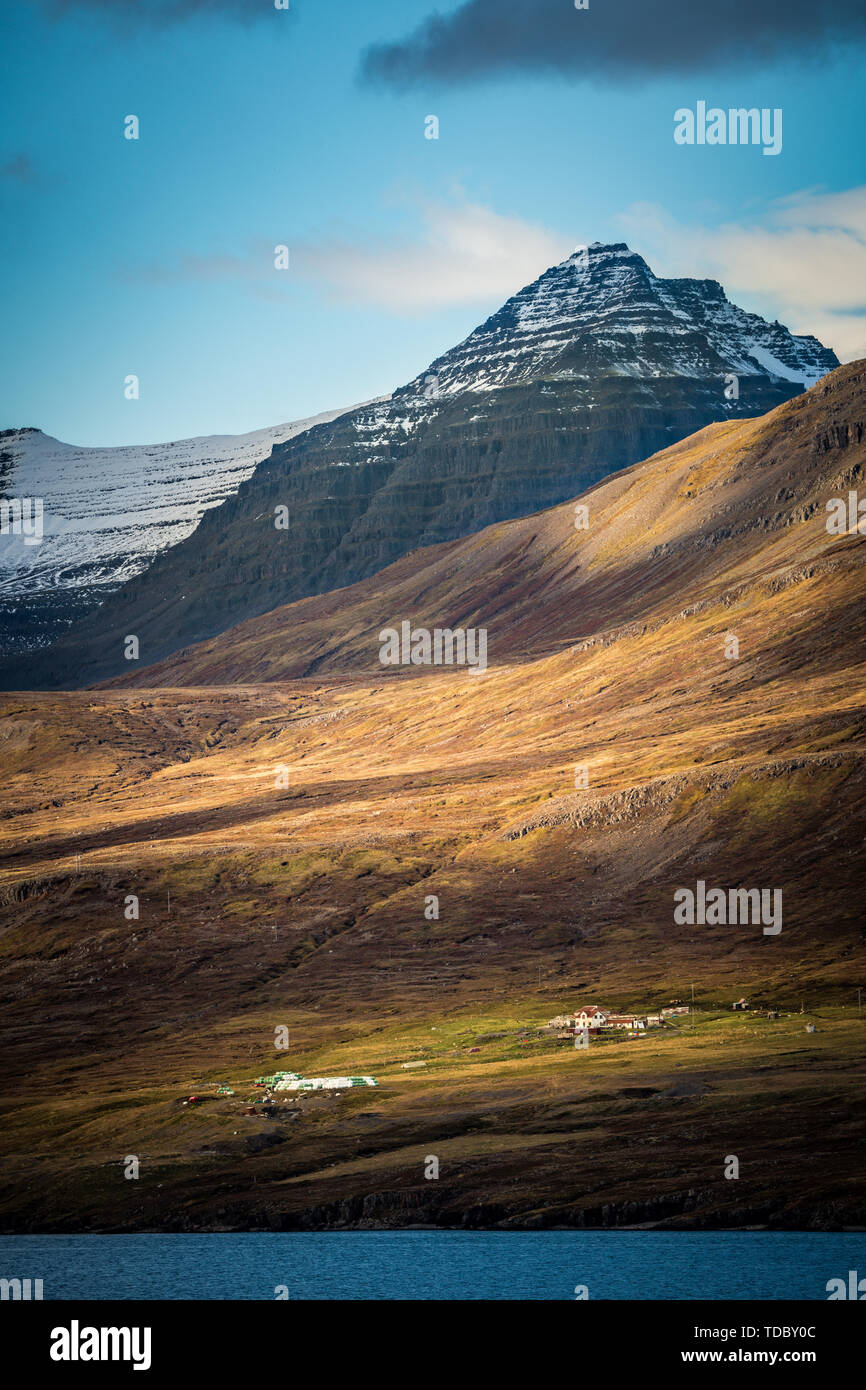 Eine ruhige Farm Cottage unter die schneebedeckten Berge des Isländischen herbst Meer Stockfoto