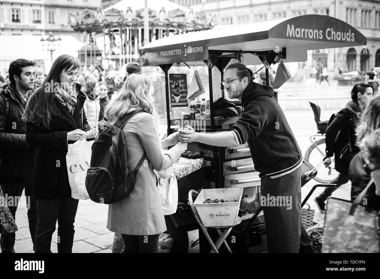 Straßburg, Frankreich - 28 Oktober 2017: Ambulante männliche Verkäufer von heissen Kastanien marron chauds auf den Straßen der französischen Stadt Kunden mit Bio-lebensmitteln traditionellen elsässischen Street Food - Schwarz und Weiß, Stockfoto