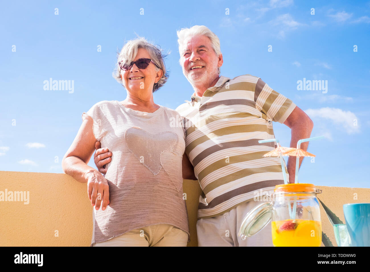 Paar der Älteren im Alter von trinken Fruchtsaft auf der Dachterrasse mit wunderschönem Blick auf das Meer. Ferienhäuser und pensionierte Konzept Stockfoto Paar der Älteren im Alter von trinken Fruchtsaft auf der Dachterrasse mit wunderschönem Blick auf das Meer. Ferienhäuser und pensionierte Konzept Stockfoto