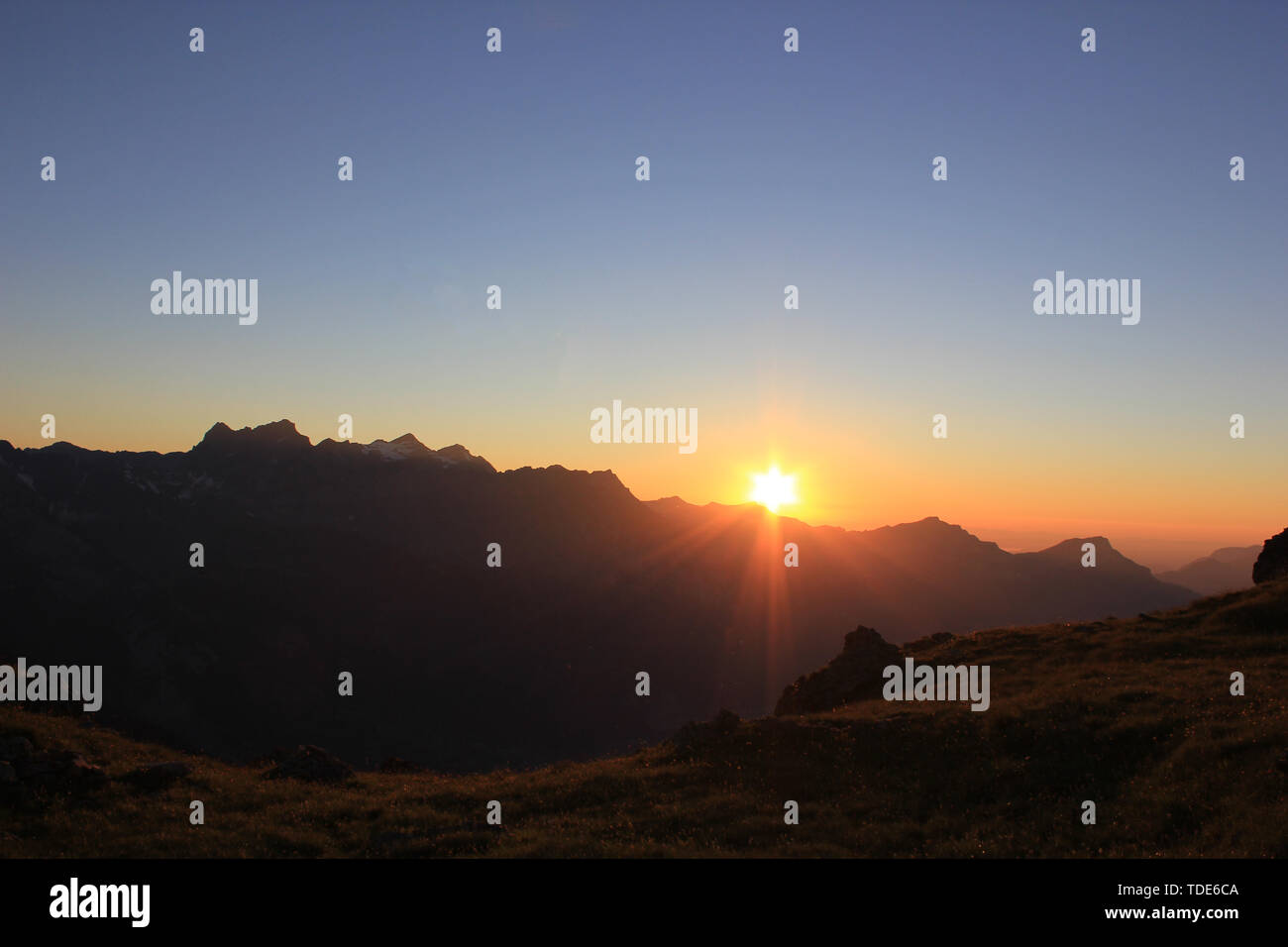 Sonnenuntergang in den Schweizer Bergen mit einem die Sonne hinter den Bergen Stockfoto