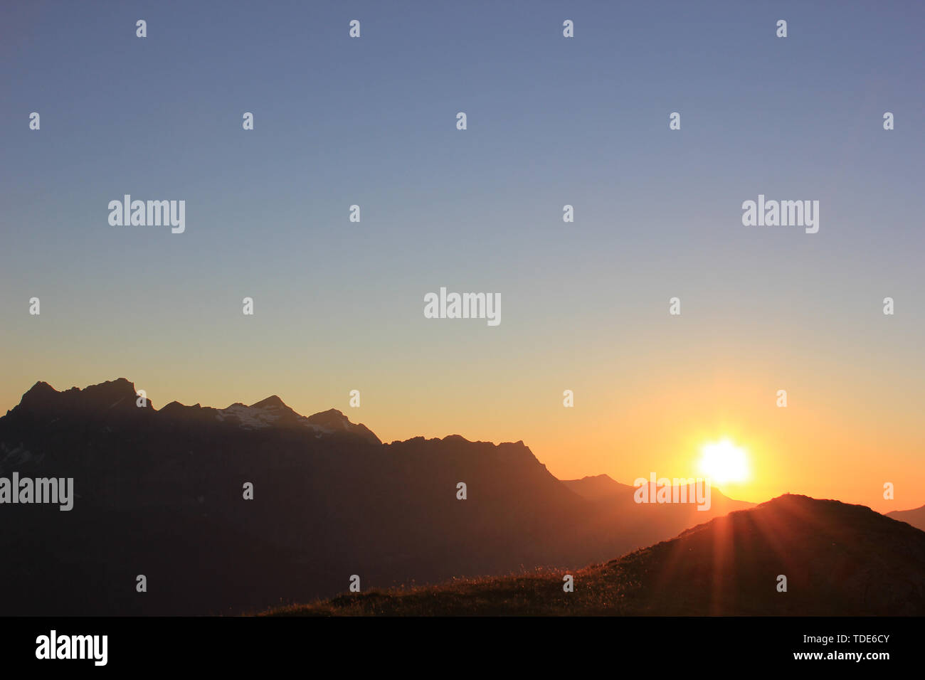Sonnenuntergang in den Schweizer Bergen mit einem die Sonne hinter den Bergen Stockfoto