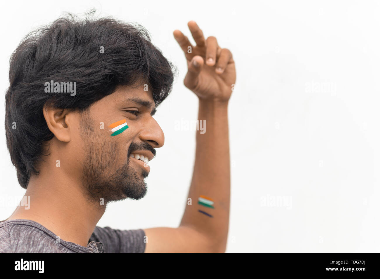 Porträt der Jungen fröhlichen Indischen männlichen Cricket Sport lackiert indische Flagge auf seinem Gesicht und Hand Geste der Sieg. Stockfoto