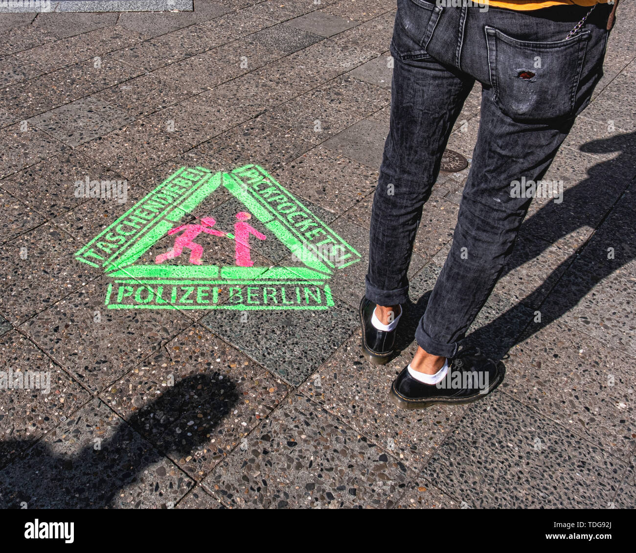 Schablone auf Bürgersteig und Mann mit Brieftasche auf eine Kette in der Tasche. Warnung vor Taschendieben Polizei & Diebe auf Bürgersteig in Kreuzberg-Berlin Stockfoto