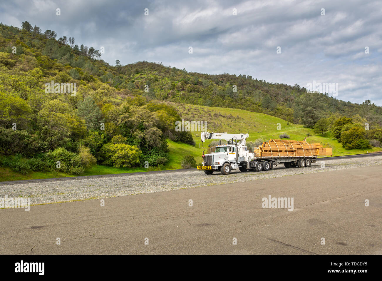 Kalifornien, USA, 4. April 2019: Big Truck mit Überbreite unterzeichnen und Step down Trailer transportieren und für den Transport von Holz. Stockfoto