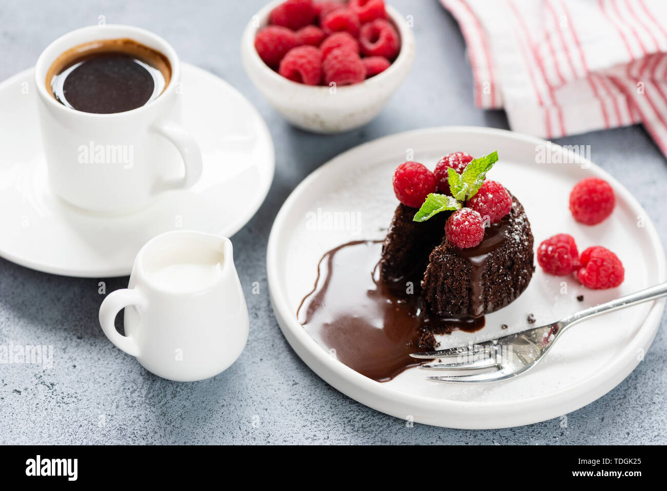 Heiße Schokolade lava Kuchen oder Schokolade Fondant auf weiße Platte mit Himbeeren und Tasse Kaffee Stockfoto
