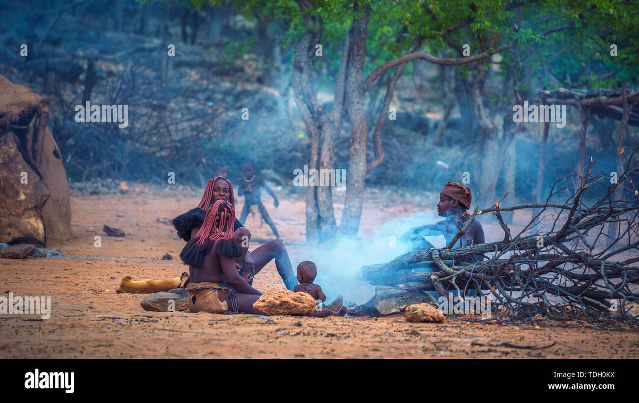 Volk der Himba sitzen um Feuer in ihrem Dorf Stockfoto