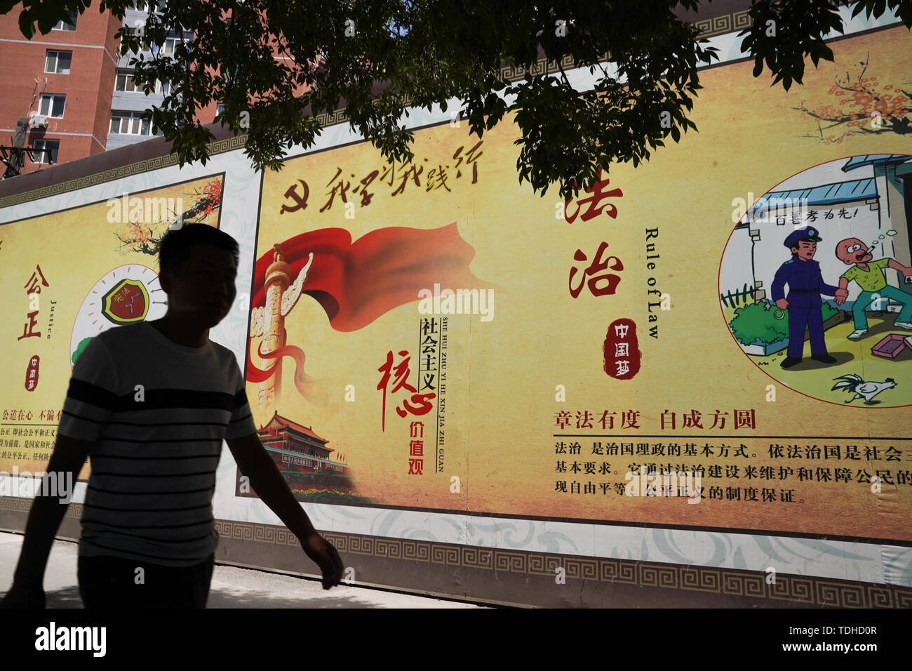 Peking, China. 14 Juni, 2019. Ein Mann hinter einem Propaganda banner beschreiben die Werte der Chinesischen Kommunistischen Partei an den Straßen in Peking. Credit: SOPA Images Limited/Alamy leben Nachrichten Stockfoto