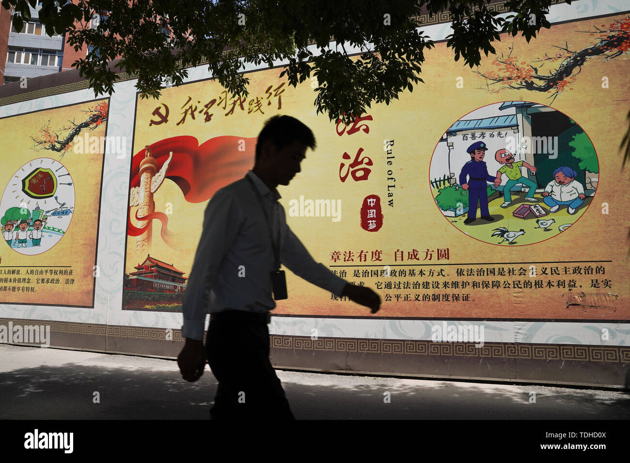 Peking, China. 14 Juni, 2019. Ein Mann hinter einem Propaganda banner beschreiben die Werte der Chinesischen Kommunistischen Partei an den Straßen in Peking. Credit: SOPA Images Limited/Alamy leben Nachrichten Stockfoto