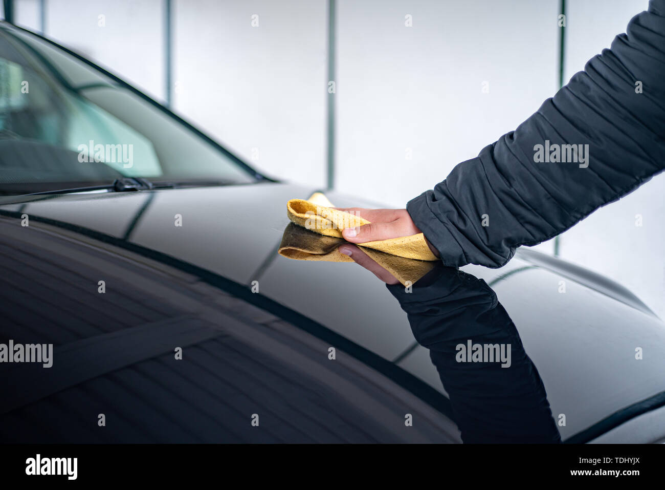 Eine Person poliert die Motorhaube auf seinem Auto mit Leder Tuch Stockfoto