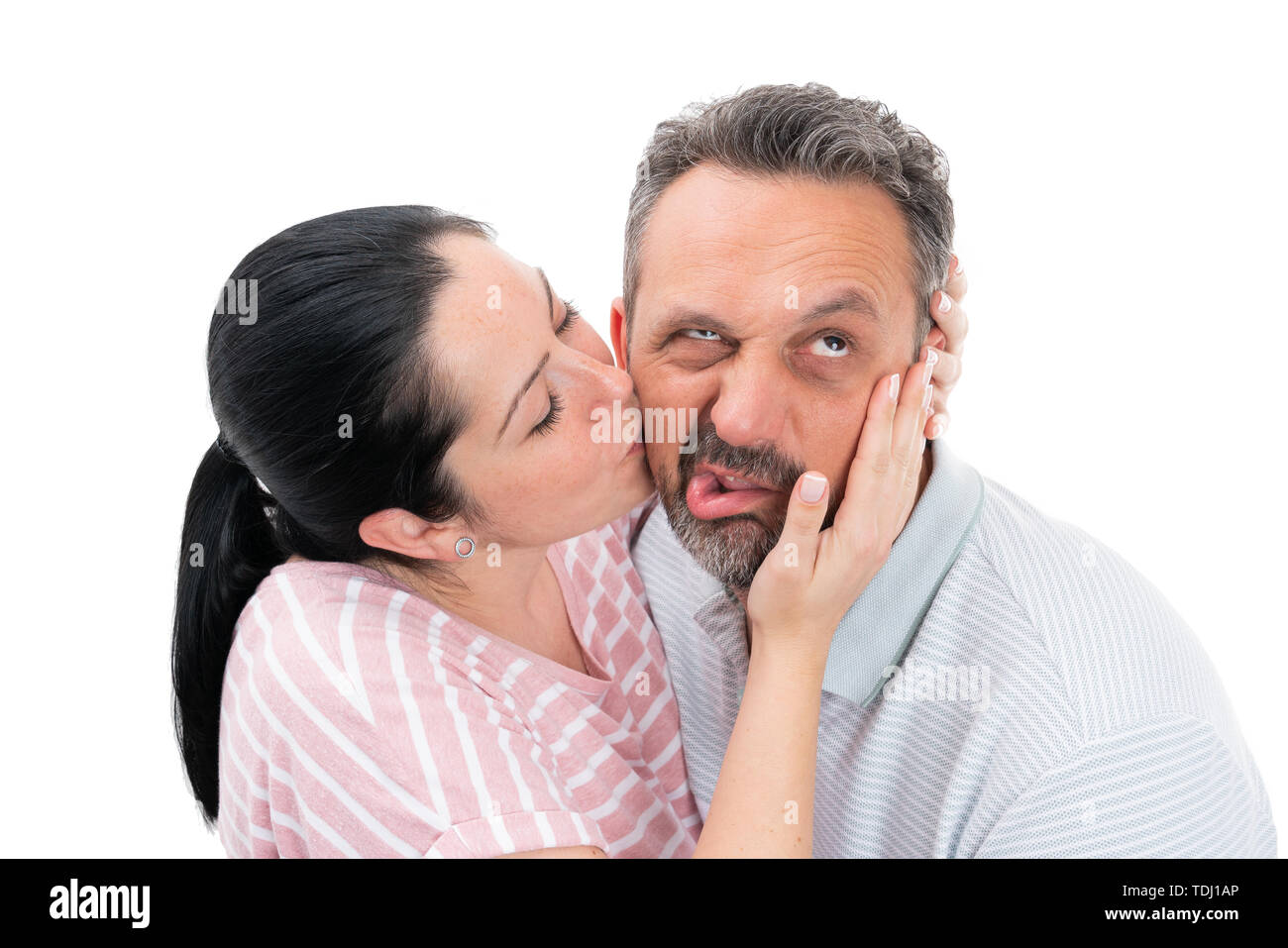 Liebevolle Frau Gesicht zu berühren und küssen Mann Wange mit angewiderten Ausdruck als Paar Konzept auf weißem Hintergrund Stockfoto