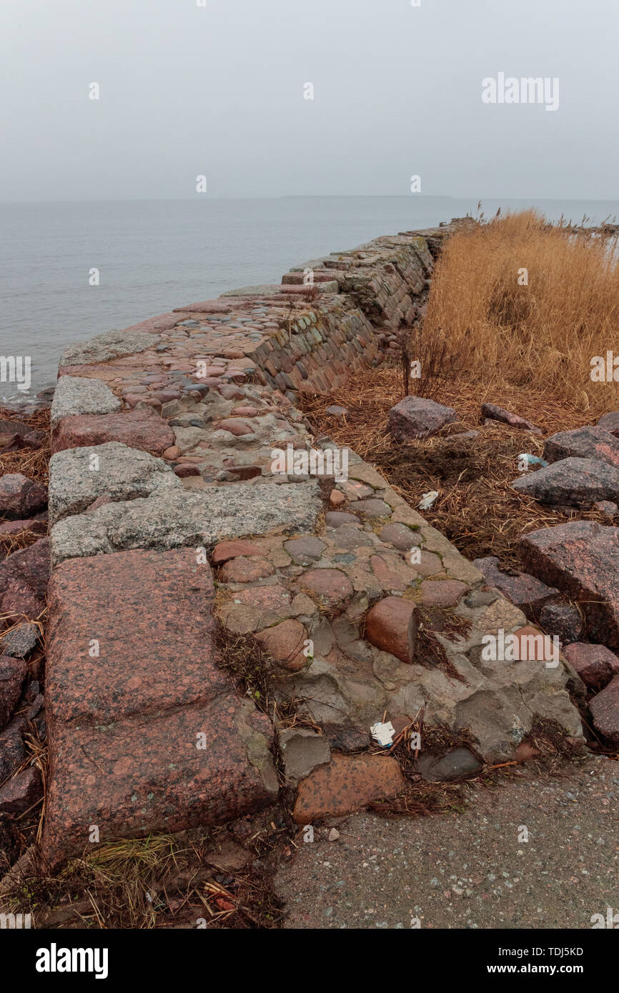 Alte und kaputte Stone Fence gegen das Meer und Himmel am Abend Stockfoto