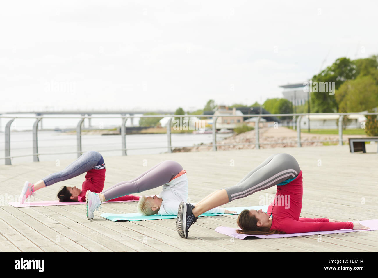 In voller Länge Porträt von drei zeitgenössischen Frauen Yoga und Stretching, Kopie im freien Raum Stockfoto