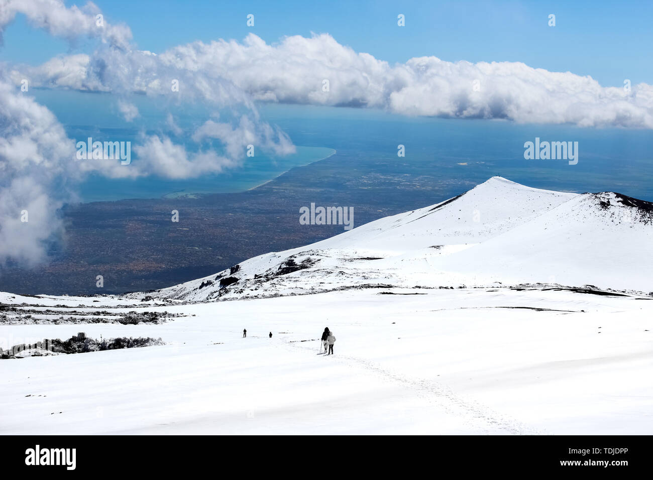Herrliche Aussicht von den Ätna fotografiert mit Wanderern hinunter auf den Schnee und das Meer im Hintergrund. Herrliche Wolken in der Nähe der Gipfel des Berges. Ätna, Sizilien, Italien. Stockfoto
