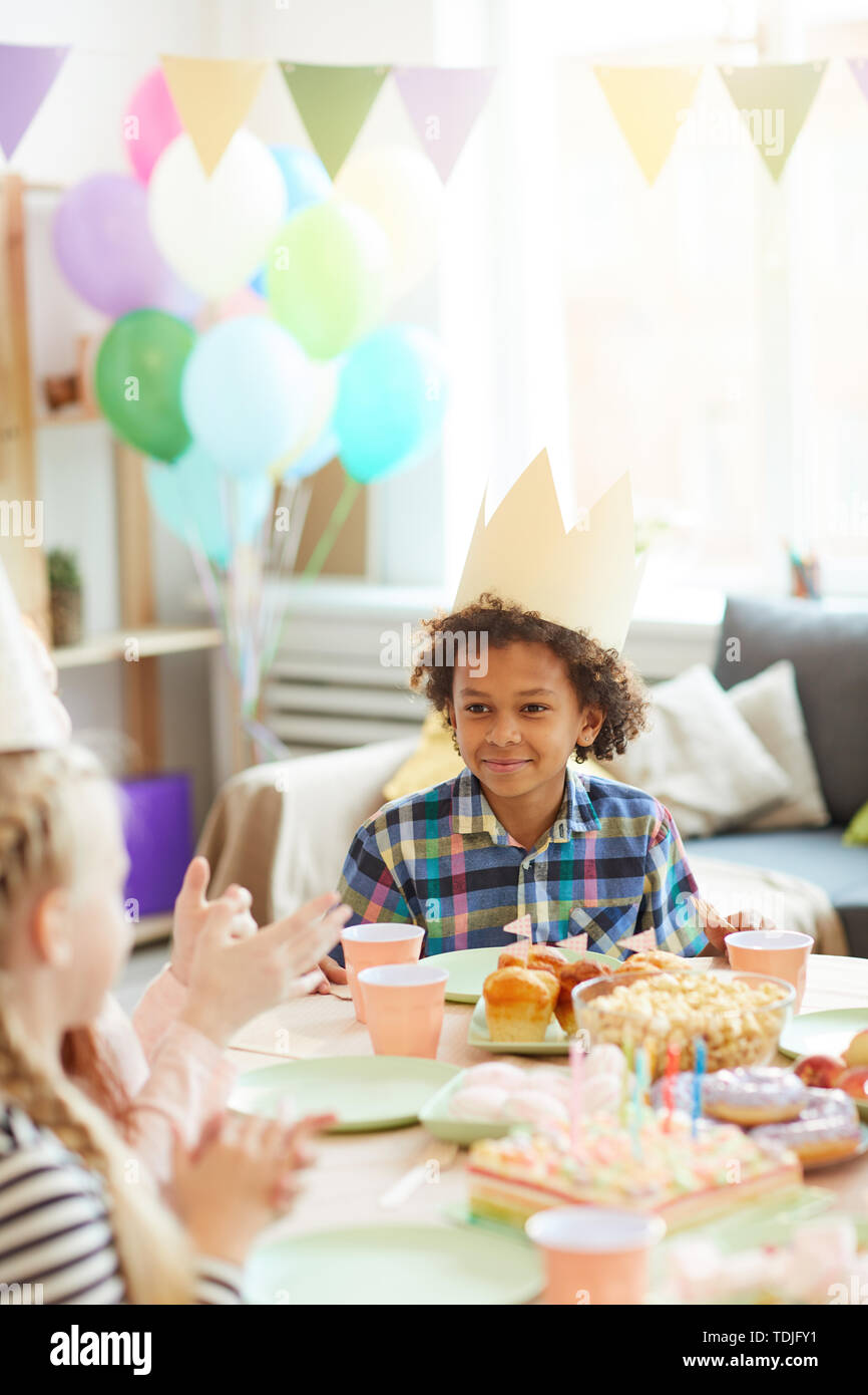 Portrait von lächelnden Afrikaner - Junge tragen Krone sitzen am Tisch beim Feiern Geburtstag mit Freunden Stockfoto