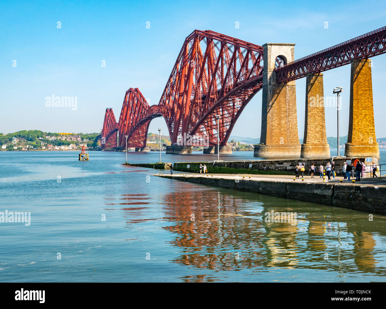 Iconic Forth Rail Bridge über die Firth-of-Forth mit Touristen auf Pier an einem sonnigen Tag, Schottland, Großbritannien Stockfoto