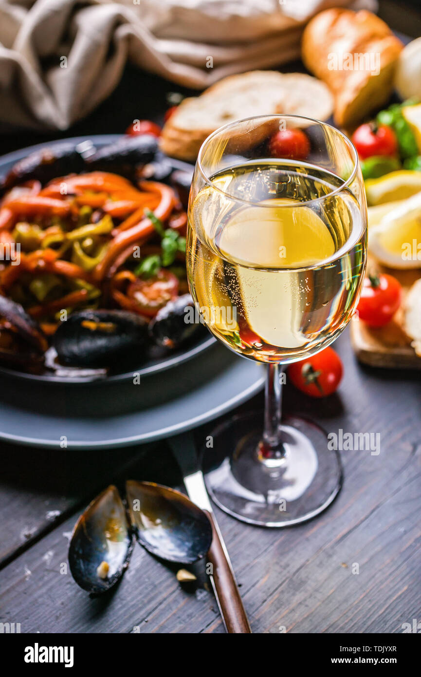 Ein Glas trockenen Weißwein auf dem Hintergrund der Italienischen Küche. Pasta, Muscheln und Wein. Stockfoto