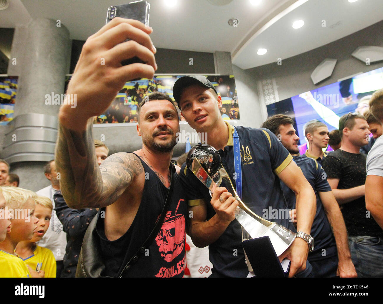 Ukrainische defender Walerij Bondar (R) stellt mit einem Ventilator für ein Foto mit der FIFA U-20-Weltmeisterschaft 2019 Trophäe, während der nationalen Teams Ankunft am Internationalen Flughafen Boryspil in Kiew, Ukraine. Die ukrainische Nationalmannschaft gewann ihr erstes FIFA U-20-Weltmeisterschaft 2019 Titel nach dem Sieg gegen Südkorea 3 - 1 in der Endrunde in Lodz, Polen. Stockfoto