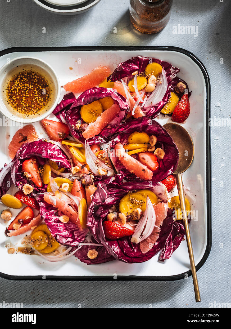 Radicchio Salat mit Regenbogen Karotten, Beeren, Früchten und Haselnüsse in Weiß Tablett serviert. Stockfoto