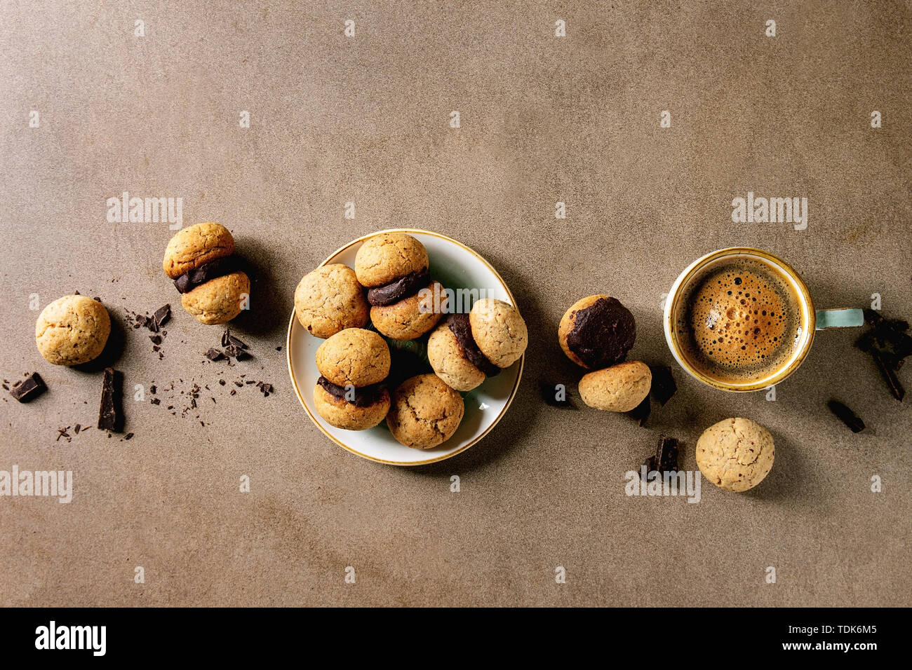 Baci di dama hausgemachte italienische Haselnuss Kekse Kekse mit Schokolade in Keramik Platte mit Tasse Espresso Kaffee über braune Textur ba serviert. Stockfoto