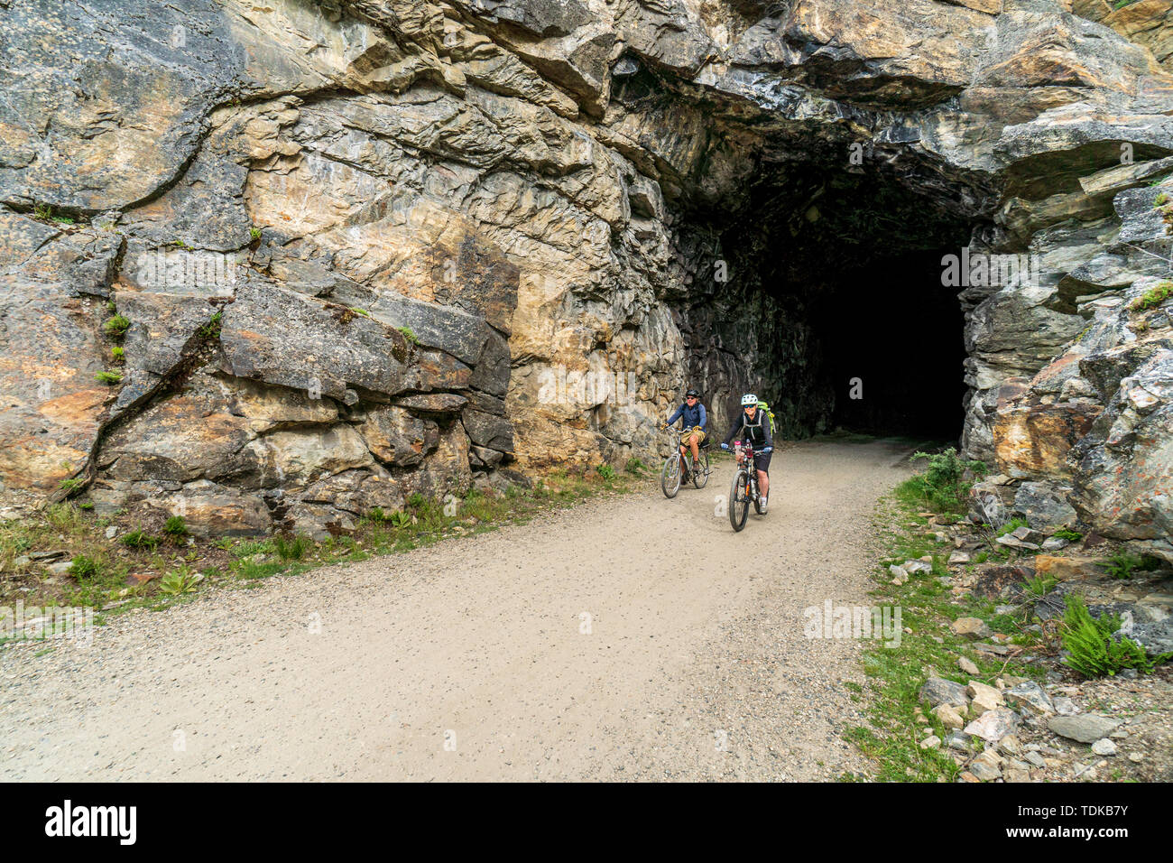 Paar Radfahren in einem der Tunnel der Kettle Valley Railway (KVR) eine verlassene Eisenbahn zu einem Wander-/Radweg umgewandelt. Stockfoto