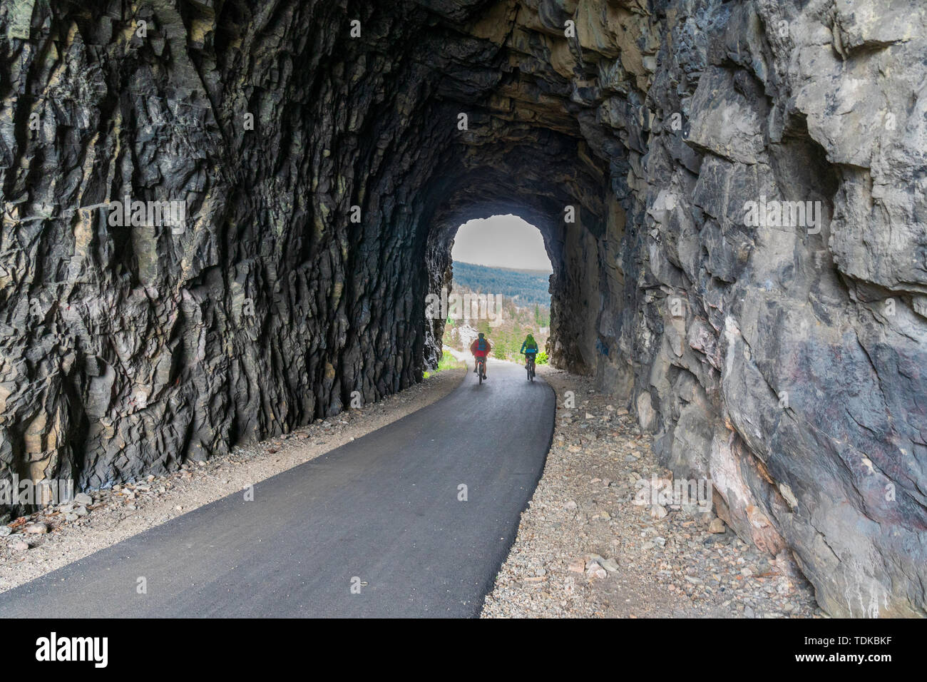Paar Radfahren in einem der Tunnel der Kettle Valley Railway (KVR) eine verlassene Eisenbahn zu einem Wander-/Radweg umgewandelt. Stockfoto