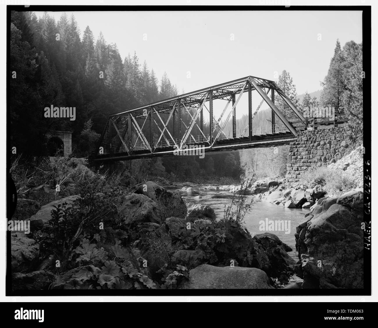 Schrägansicht der vorderen Seite der Brücke Nr. 310.58, 135-mm-Objektiv. Hinweis ashlar Steinmetzkunst Widerlager, 1886, Tunnel 15 auf der linken Seite. Schwere Vegetationsbedeckung, steilen Ufern und fehlende streamside Grundlage ausgeschlossen, volle Höhe Blick auf die vor- und nachgelagerten Seiten dieser Brücke. - Southern Pacific Railroad Shasta Route, Brücke Nr. 310.58, 310.58 Milepost, Sims, Shasta County, CA Stockfoto