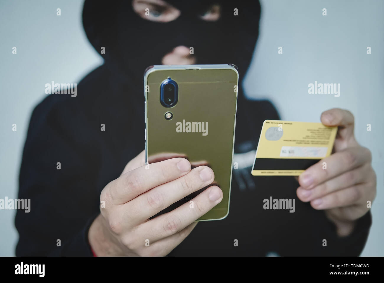 Cyber Kriminelle in balaclava trägt die Informationen von einem persönlichen Konto. Kreditkarte betrügerisch. Diebstahl von cyber Geld mit mobilen. Neue w Stockfoto