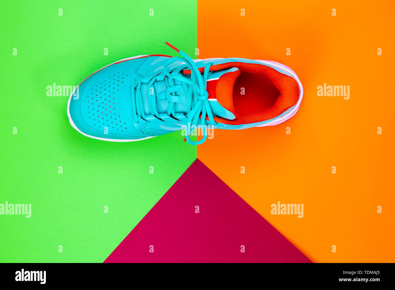 Rot, Hellblau, Weiß neu Tennisschuh im Studio Schuß über grün, orange, lila Hintergrund. Direkt von oben. Stockfoto