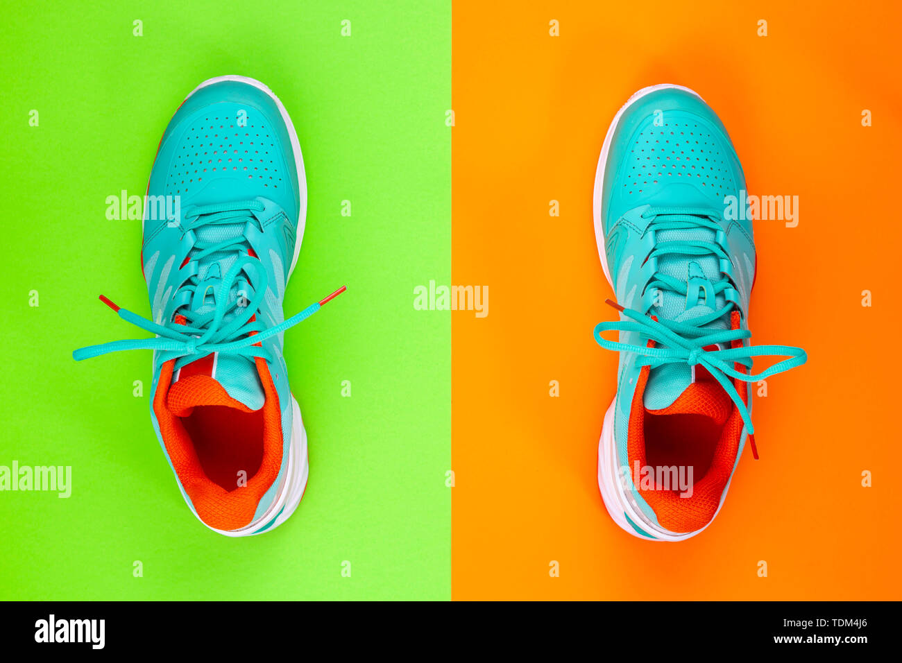 Rot, hellblau, weiß, Paar neue Tennisschuhe im Studio Schuß über grün, orange Hintergrund. Direkt von oben. Stockfoto