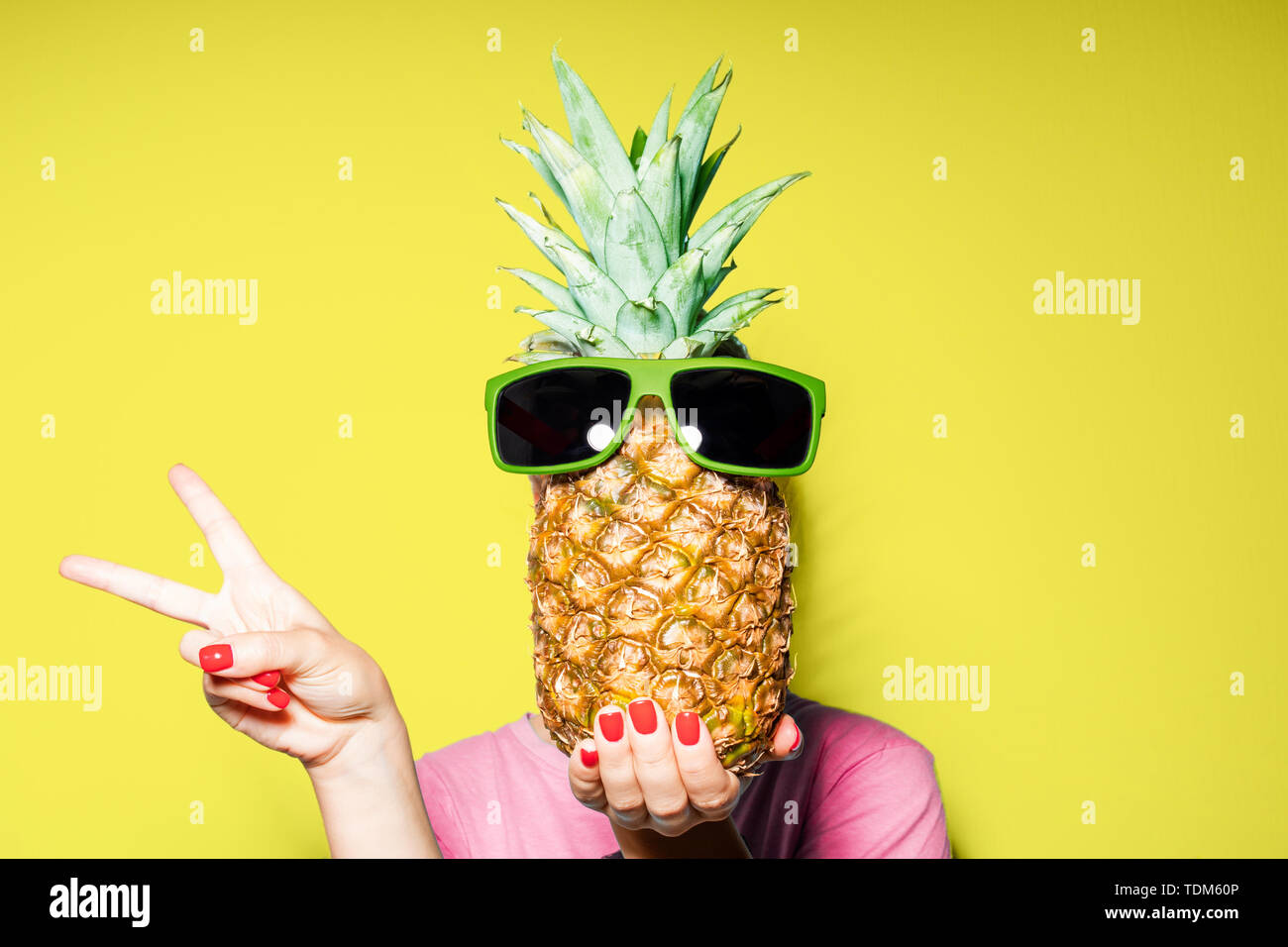 Mode portrait Frau und Ananas mit Sonnenbrille versteckt sich Kopf über Farbe Hintergrund Stockfoto