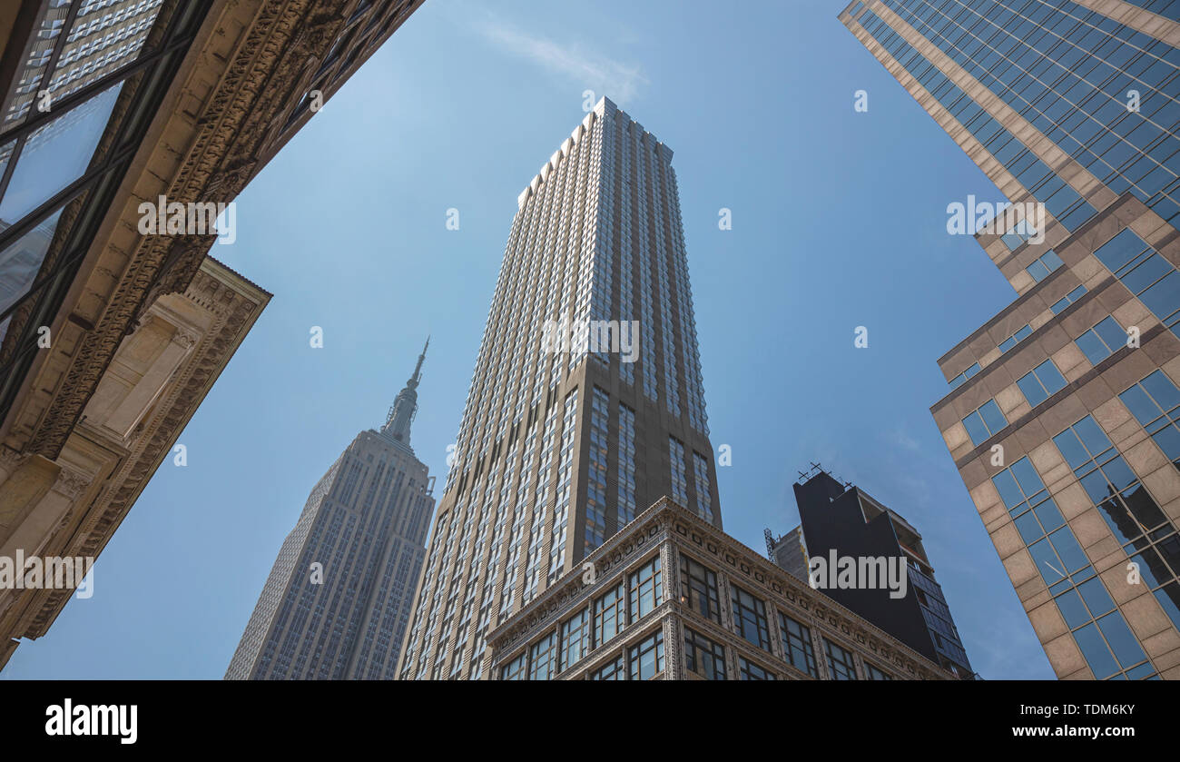 New York, Manhattan kommerziellen Zentrum. Wolkenkratzer und Empire State Building Perspektive gegen den blauen Himmel Hintergrund, Low Angle View, Feder sunn Stockfoto