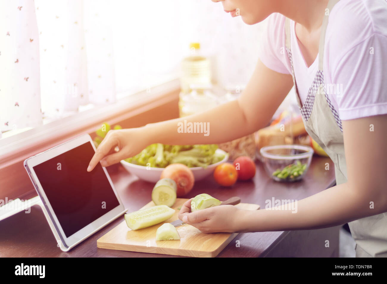 Asiatische Frau mit Finger auf Tablet Bildschirm vorbereiten Zutaten zum Kochen folgen Kochen online Video Clip auf der Website. Kochen Inhalten im Internet Stockfoto