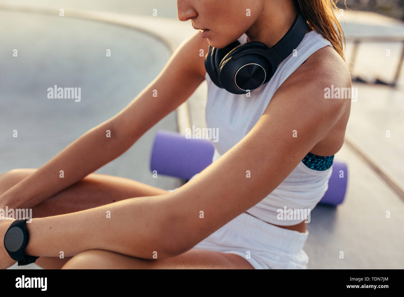 In der Nähe der weiblichen Sitzen im Freien mit Kopfhörer um den Hals nach dem Workout. Frau ausruhen nach Sport Training. Stockfoto