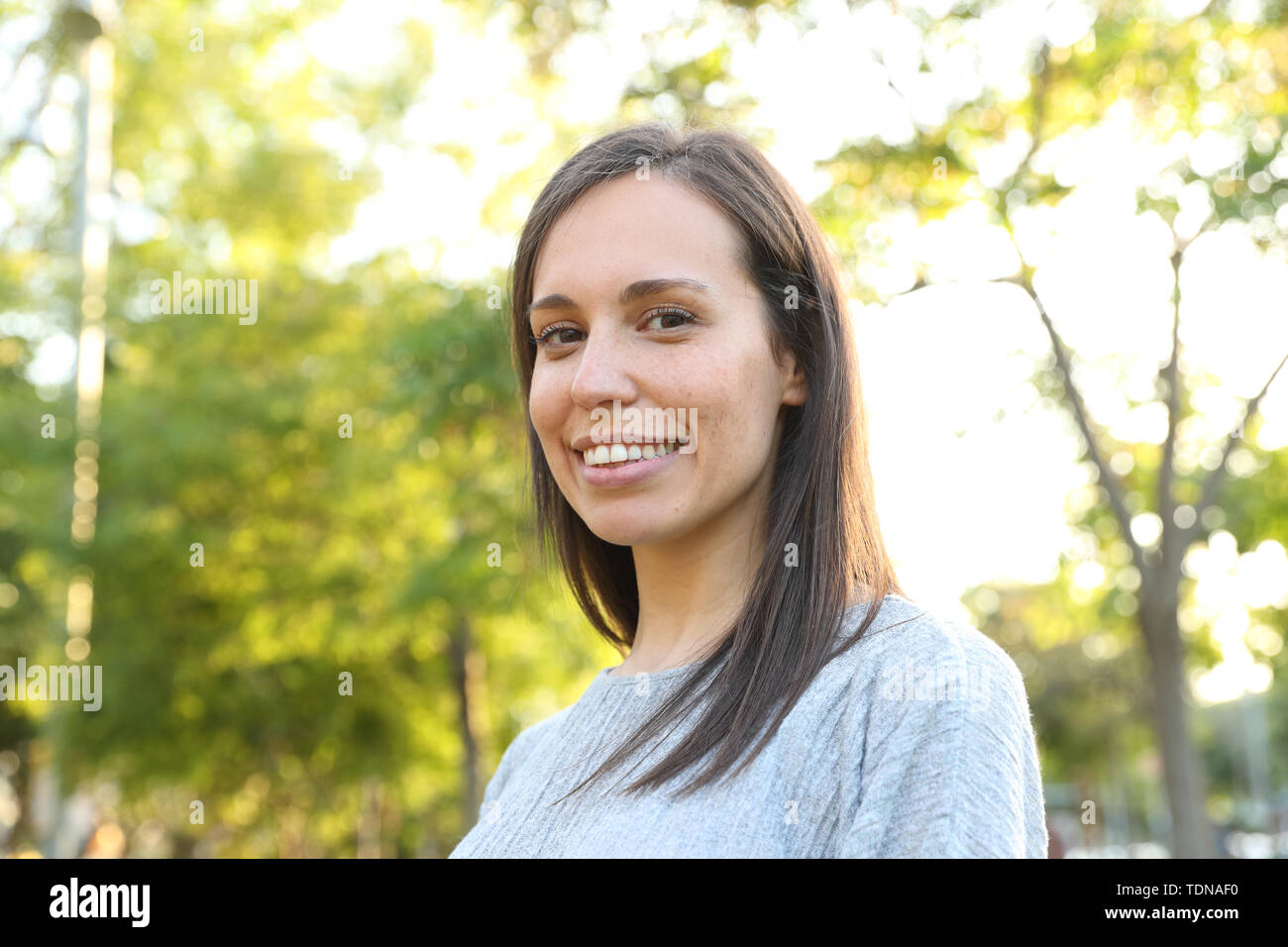 Glückliche Frau an der Kamera stehend in einem grünen Park suchen Stockfoto