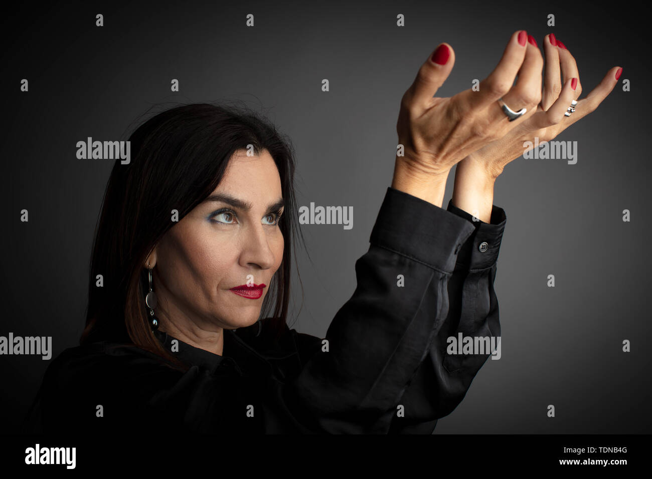 Portrait von Frau mittleren Alters Interaktion mit Händen, dunkelgrauer Hintergrund. Stockfoto