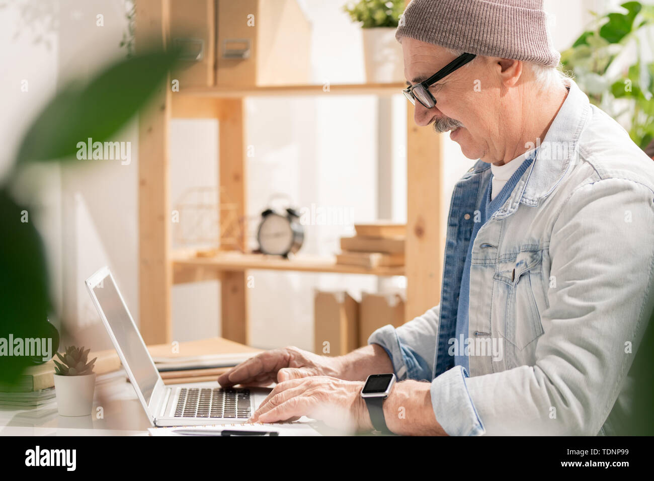 Seitenansicht des beiläufigen reifen Designer auf der Suche nach Laptop Display beim Surfen durch Designer websites für neue Ideen Stockfoto