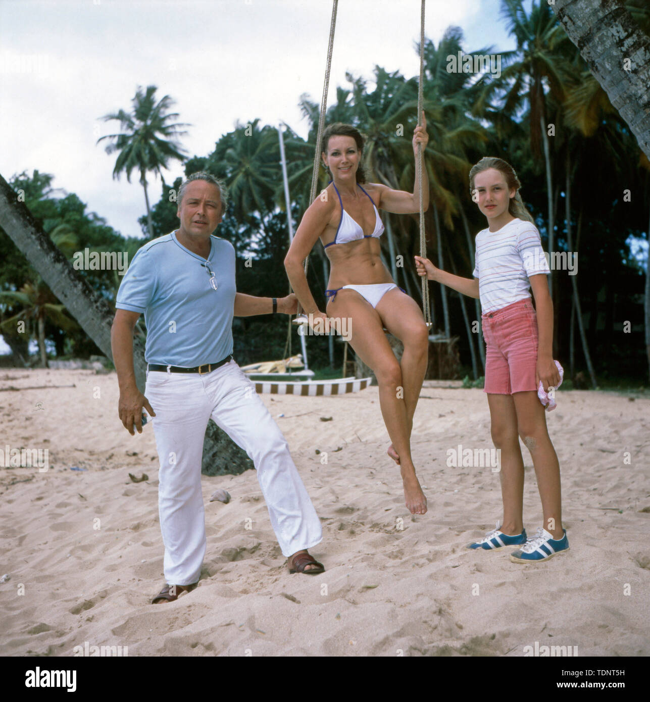 Die deutsche Fernsehmoderatorin, Programmsprecherin, Plant und ehemalige Miss World Petra Schürmann posiert schaukelnd, mit Ihrem Partner Gerhard Freund und Tochter Alexandra Freund am Strand im Bikini, Ca. 1978. Die deutsche TV-Moderator, Sprecher, Schauspielerin und ehemalige Miss World Petra Schürmann stellt mit ihrem Partner Gerhard Freund und Tochter Alexandra Freund am Strand im Bikini, Ca. 1978. Stockfoto