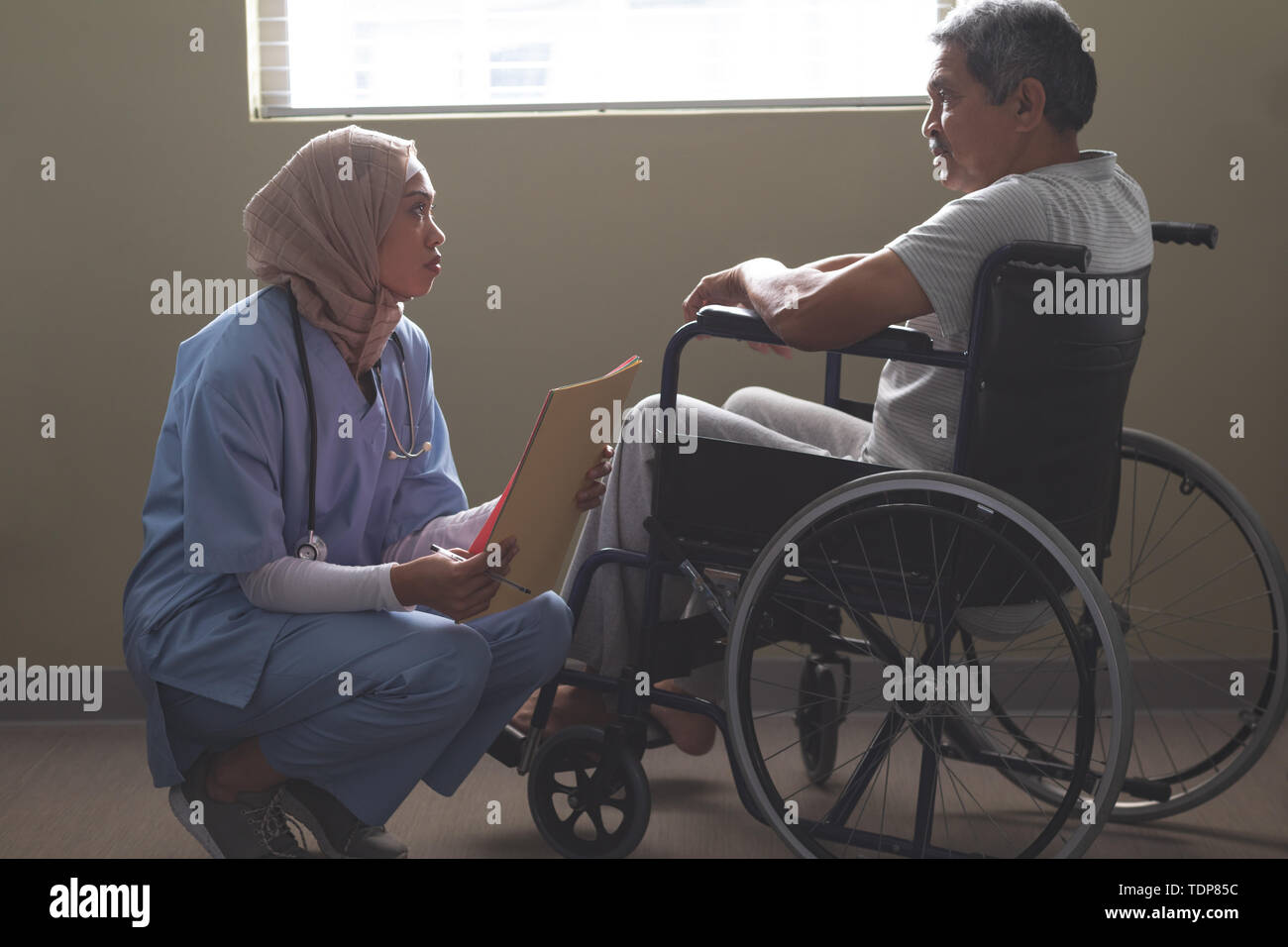 Weibliche Patienten Umgang mit Behinderten männlichen Patienten auf der Station Stockfoto