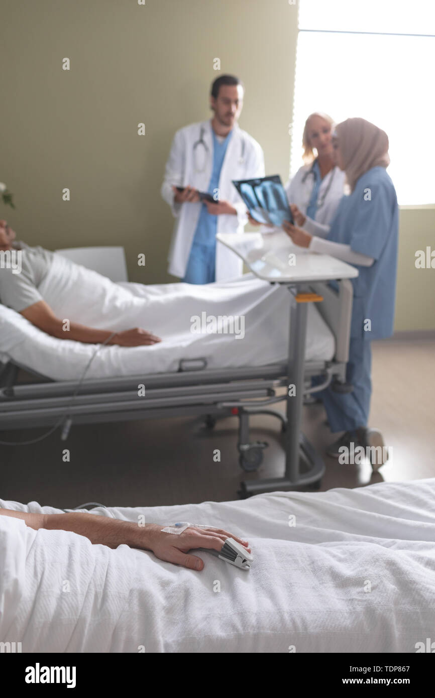 Patienten entspannen auf Bett, während Ärzte mit einander interagieren in der Gemeinde Stockfoto