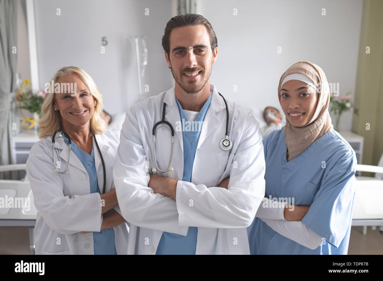 Männliche und weibliche Ärzte stehen mit den Armen in der Gemeinde überschritten Stockfoto
