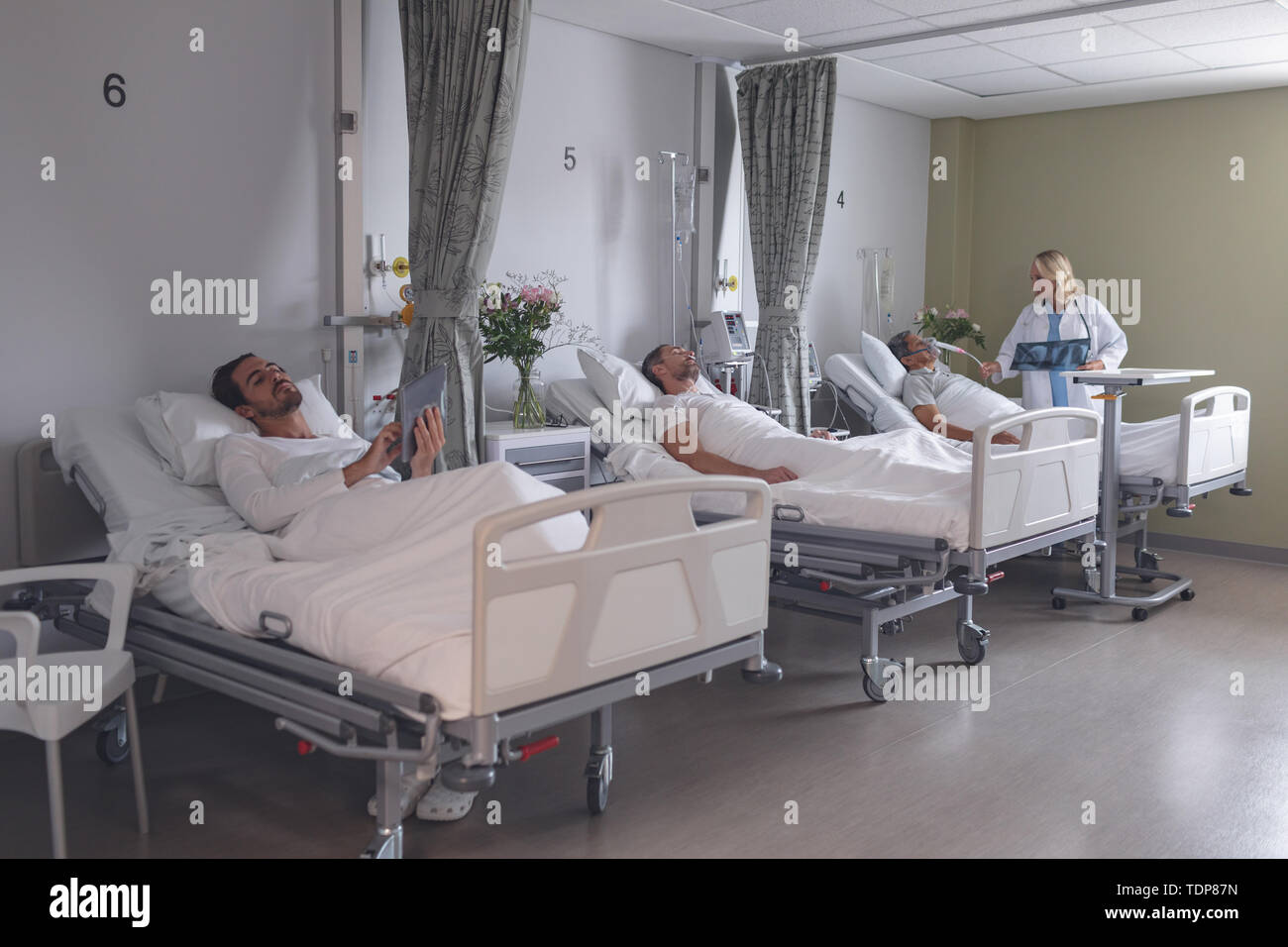Männliche Patienten mit digitalen tablet, während die weiblichen Arzt prüfen männlicher Patient in der Gemeinde Stockfoto
