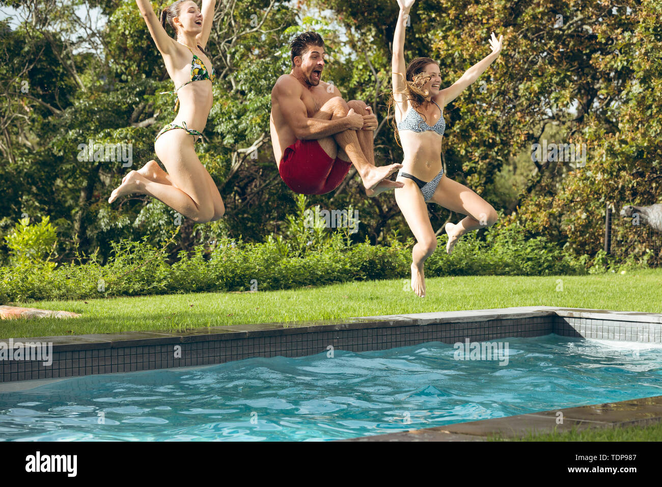 Männliche und weibliche Freunde im Pool im Hinterhof springen Stockfoto