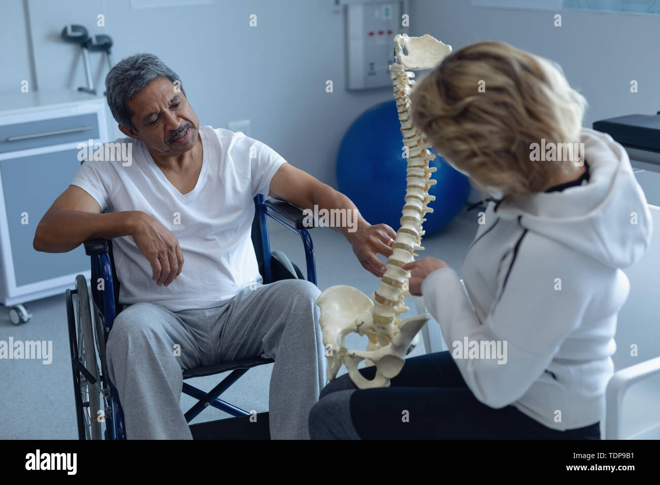 Weibliche Physiotherapeut erklärt Wirbelsäule Modell männlicher Patient Stockfoto