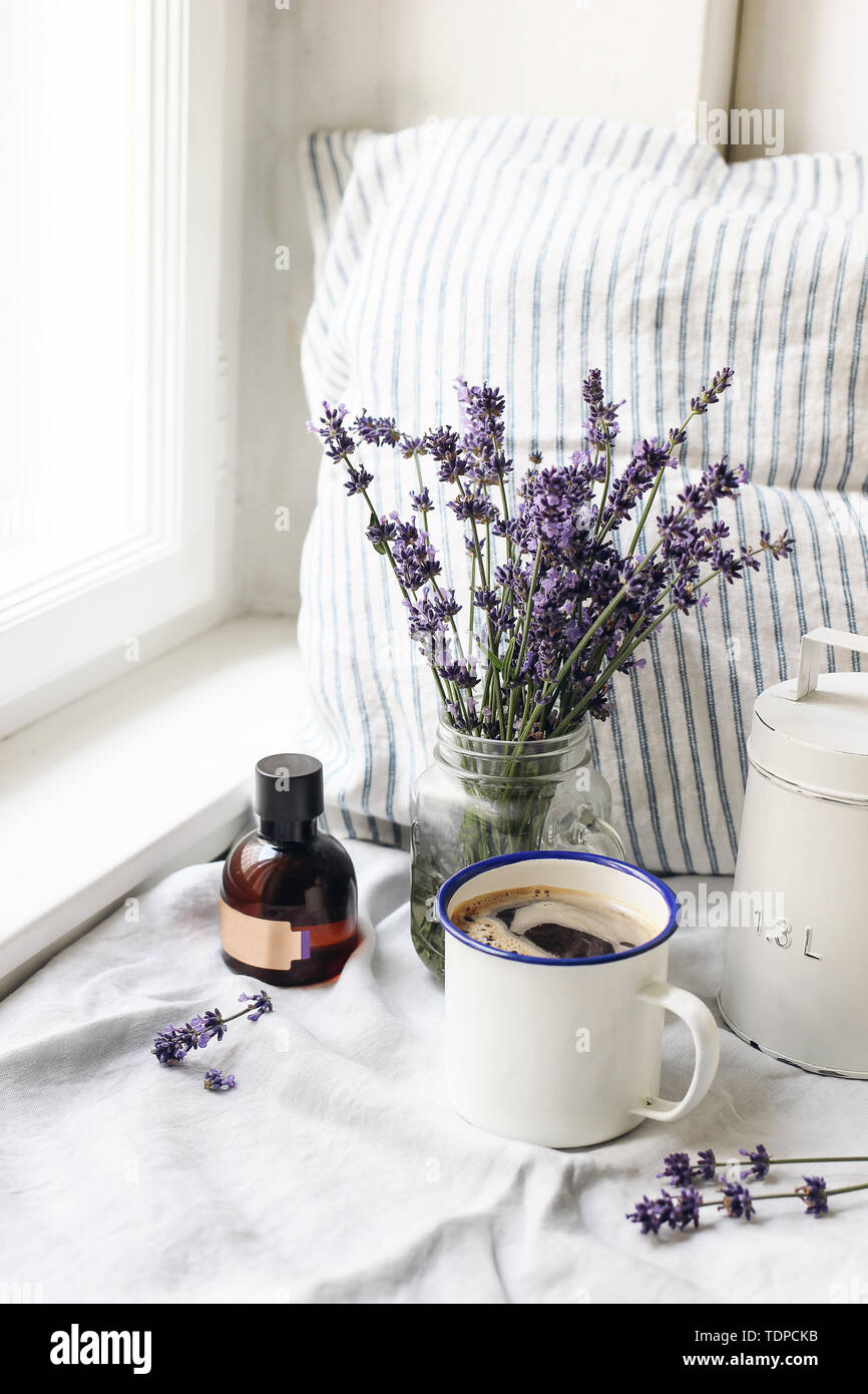 Französische Sommer noch leben. Tasse Kaffee, Lavendel Blumen Blumenstrauß, Essence öl Flasche auf der Fensterbank. Feminin Foto, blumige Komposition w Stockfoto