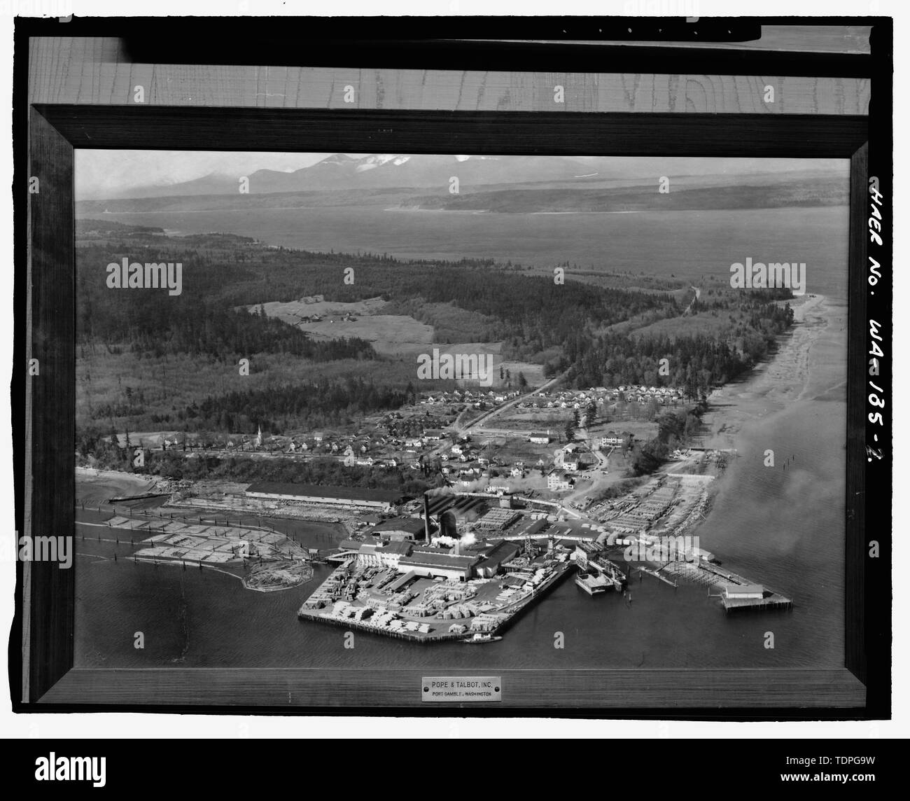 (Original drucken in Papst und Talbot Archiv Port Gamble, WA). Unbekannter Fotograf, circa 1953. Aussicht auf Port Gamble und Umgebung, Luftaufnahme mit Blick nach Westen. Port Gamble Bucht, Stadt und millsite im Vordergrund, Haube Kanal und Olympic Mountains im Hintergrund. - Port Gamble National Historic Landmark, begrenzt durch Haube Kanal, Port Gamble Bucht, State Road 104, und die Stadt Grenzen, Port Gamble, Kitsap County, WA; Ottoboni, Gina, Sender; Slemmons, Stange, Fotograf Stockfoto
