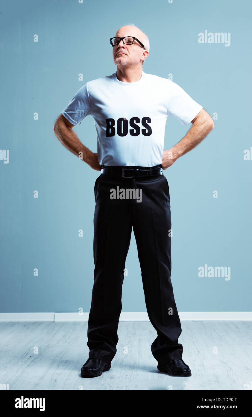 Hochmütig hochnäsig Boss stereotyp mit einem Studio geschossen von einem älteren Mann, der eine Chef T-shirt auf den Hüften schauen Sie oben und an der Seite Stockfoto