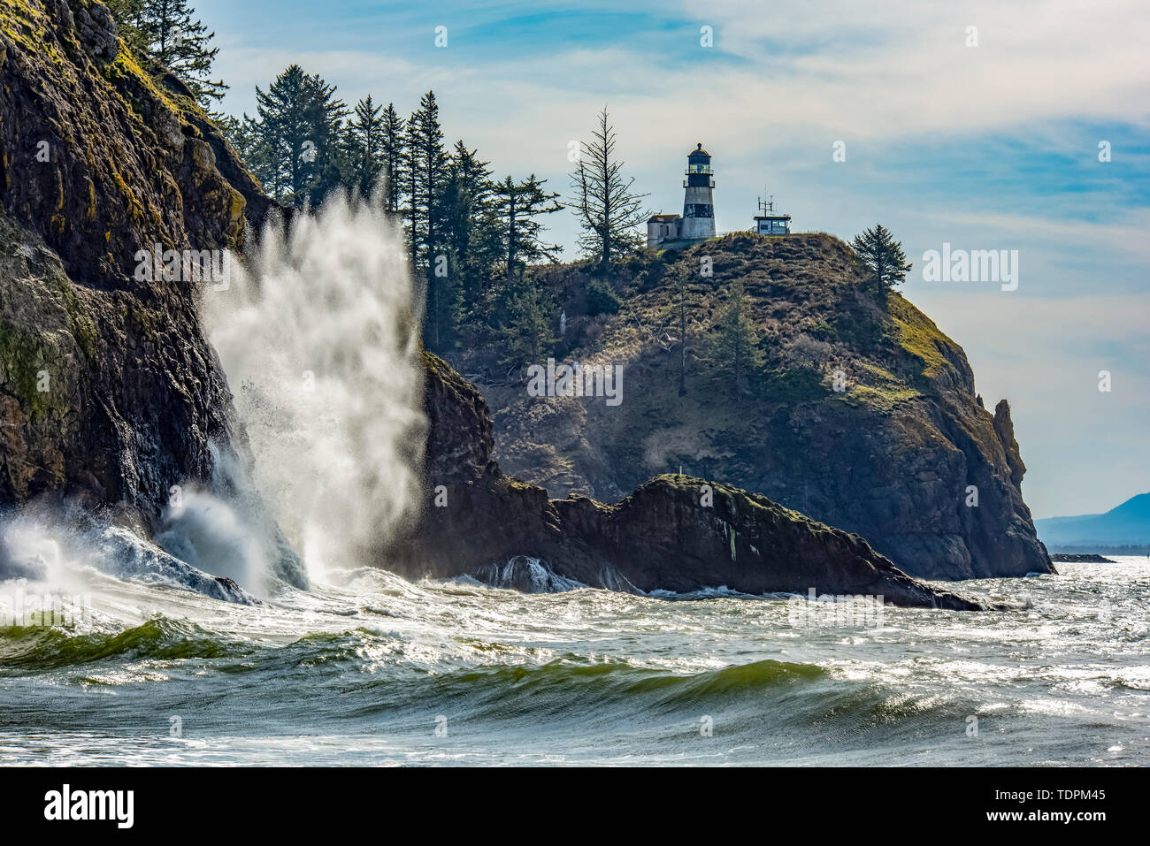 Eine Welle stürzt auf den Felsen unterhalb der Cape Enttäuschung North Head Leuchtturm an der Mündung des Columbia River. Stockfoto