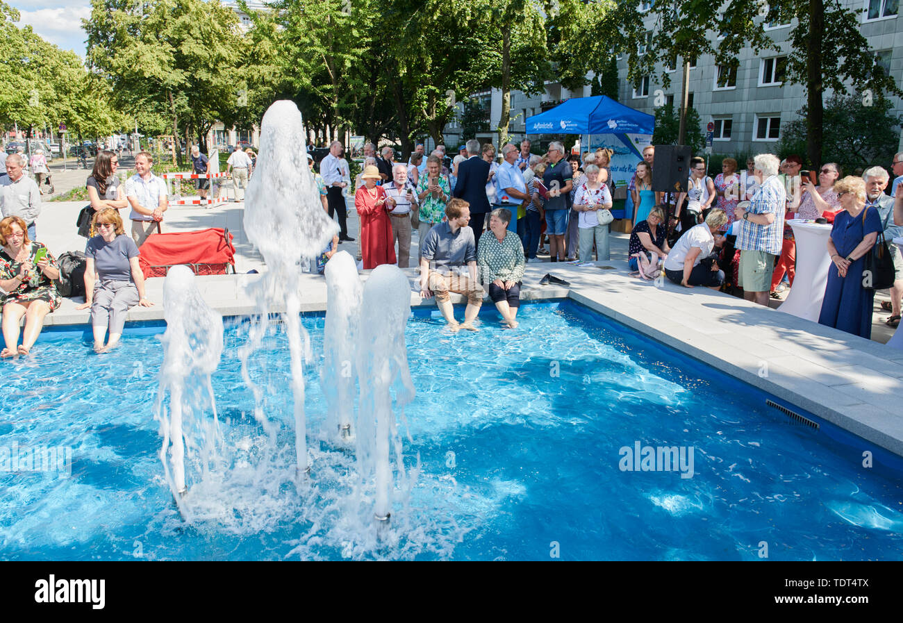 Berlin, Deutschland. Juni, 2019 18. Florian Schmidt (Bündnis 90/Die Grünen, l Sterben), Landrat Friedrichshain-Kreuzberg und Katrin Lompscher (Die Linke), Senatorin für Stadtentwicklung, sitzen an der Quelle und ihre Füße im Wasser halten. Der Brunnen in der Karl-Marx-Allee ist wieder in Betrieb zum ersten Mal nach 27 Jahren der Dürre. Quelle: Annette Riedl/dpa/Alamy leben Nachrichten Stockfoto