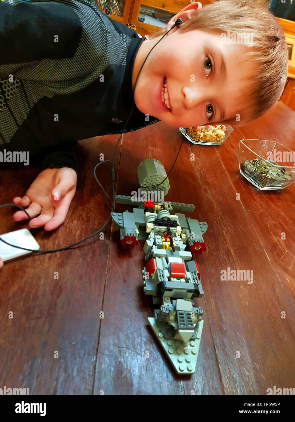 Junge Gebäude ein Raumschiff mit LEGO Musik hören, Deutschland Stockfoto