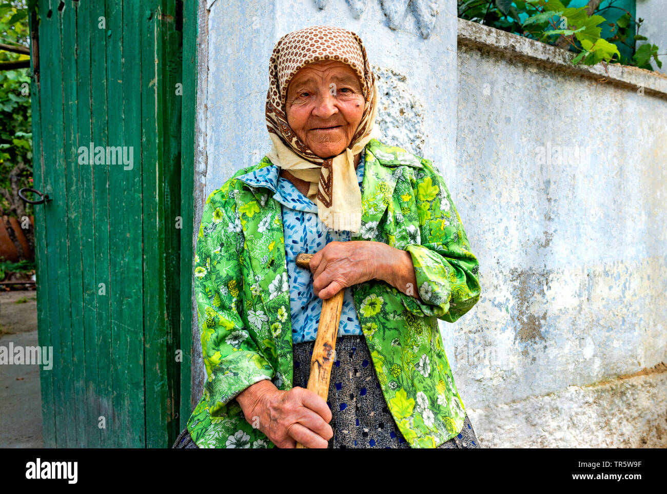 Alte Frau mit Stock vor dem Gartentor, Moldau, Delacau Stockfoto